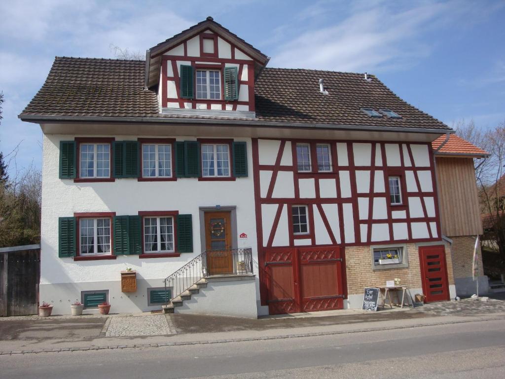Andelfingen维格曼住宿加早餐旅馆的一座带红色门和绿色百叶窗的房子
