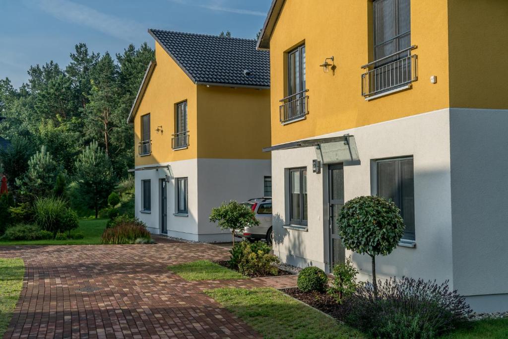 柏林Ferienpark Rübezahl am Müggelsee, Haus 21 Efeu mit eigener Sauna, idealer Ort für Natur- und Erholungssuchende, für Radfahrer, Familien mit Kindern und Hundeliebhaber的一条黄色和白色的房屋,有车道