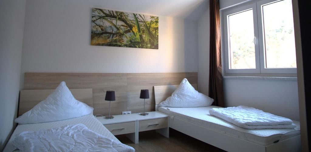 柏林Ferienpark Rübezahl am Müggelsee, Haus 22 Heide mit eigener Sauna, idealer Ort für Natur- und Erholungssuchende, für Radfahrer, Familien mit Kindern und Hundeliebhaber的有两张床和一扇窗户的卧室