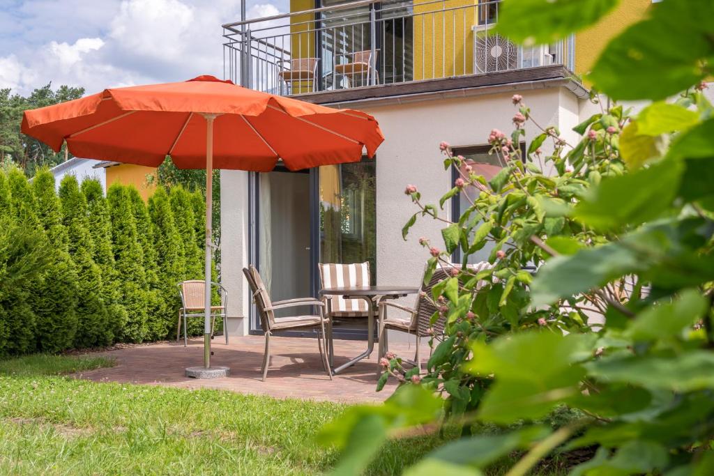 柏林Ferienpark Rübezahl am Müggelsee, Haus 22 Heide mit eigener Sauna, idealer Ort für Natur- und Erholungssuchende, für Radfahrer, Familien mit Kindern und Hundeliebhaber的露台上遮阳伞下的桌子和椅子
