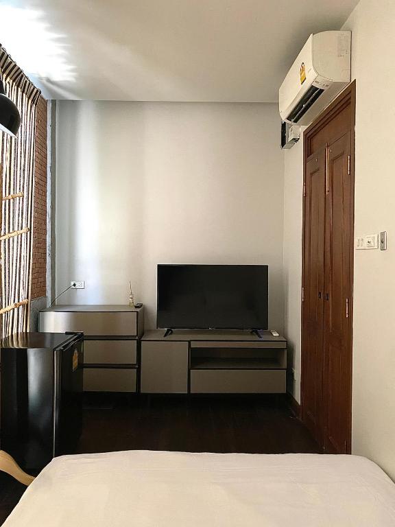 清迈Khunluang Hostel的一间卧室设有平面电视和一张床。