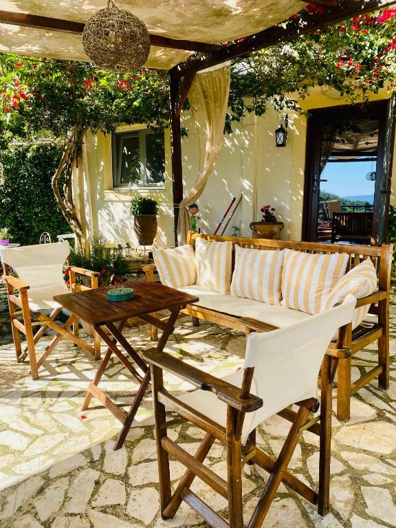 SpartýlasLorantina Luxury Sea View Holiday House close to Barbati &amp; Ipsos Beach with Starlink WiFi的庭院配有白色的椅子和木桌