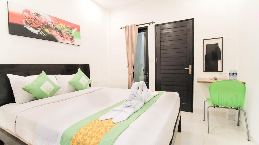 金巴兰阿卡塔拉民宿的一间卧室配有一张大床和一张绿色椅子