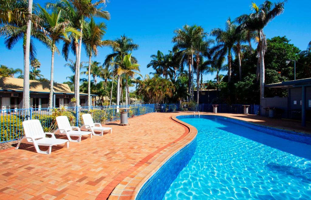 赫维湾孔戴瑞酒店的一个带白色椅子和棕榈树的游泳池