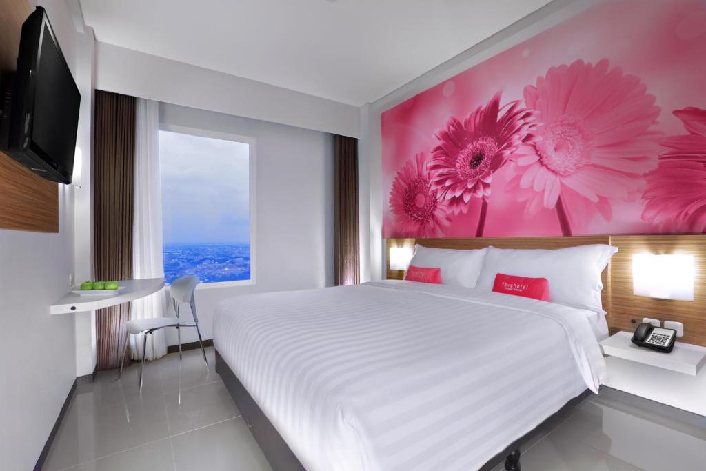 泗水泗水容库喜爱酒店的卧室配有一张大床,墙上挂着粉红色的鲜花