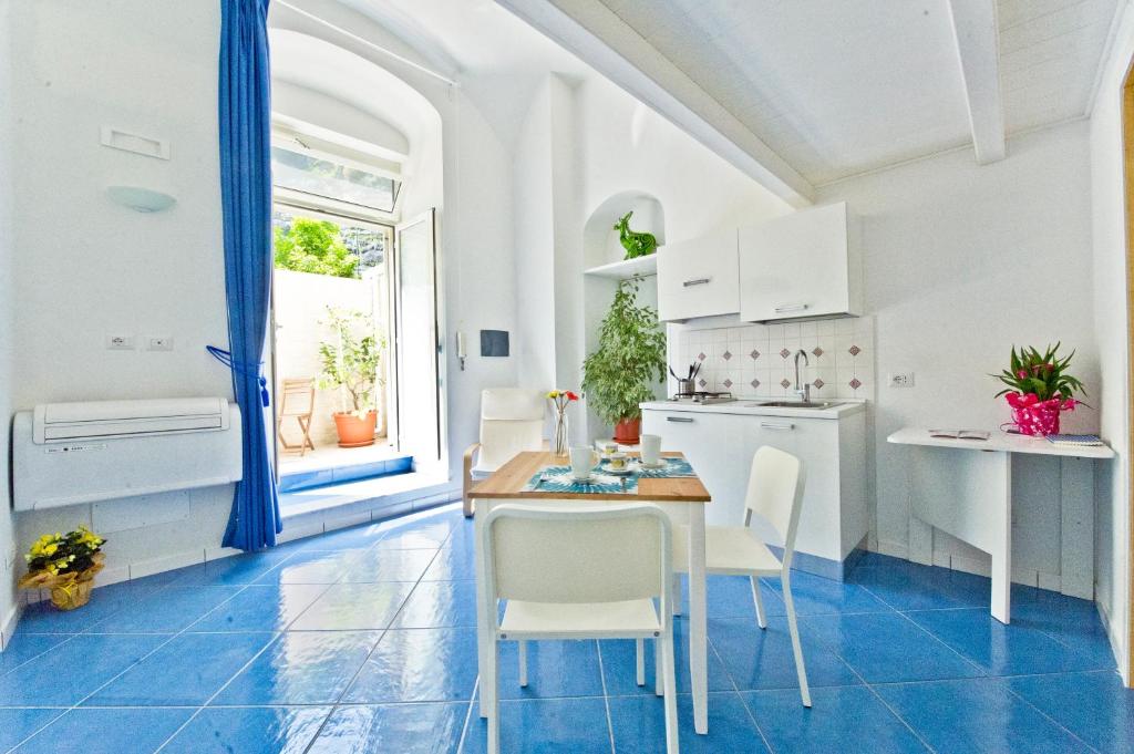 阿特拉尼Alfieri Rooms - Amalfi coast的厨房配有白色橱柜和桌椅