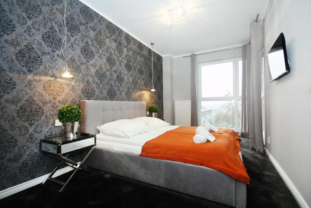 什切青丽文高档公寓的一间卧室配有一张带橙色毯子和窗户的床。