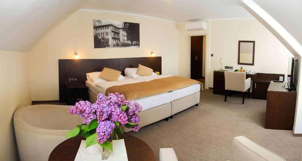 皮耶什佳尼Ensana Pro Patria的配有床和鲜花桌的酒店客房