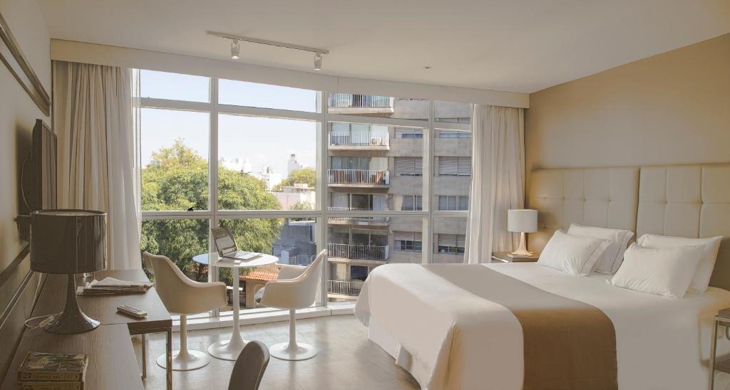 蒙得维的亚Vivaldi Hotel Loft Punta Carretas的一间卧室设有一张大床和一个大窗户