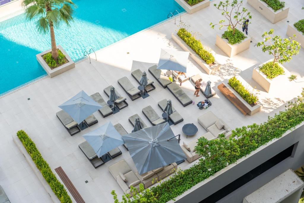 迪拜Chalet Homes - LUX New Studio With 2 Double Beds in Downtown Dubai的带椅子和遮阳伞的泳池俯视图