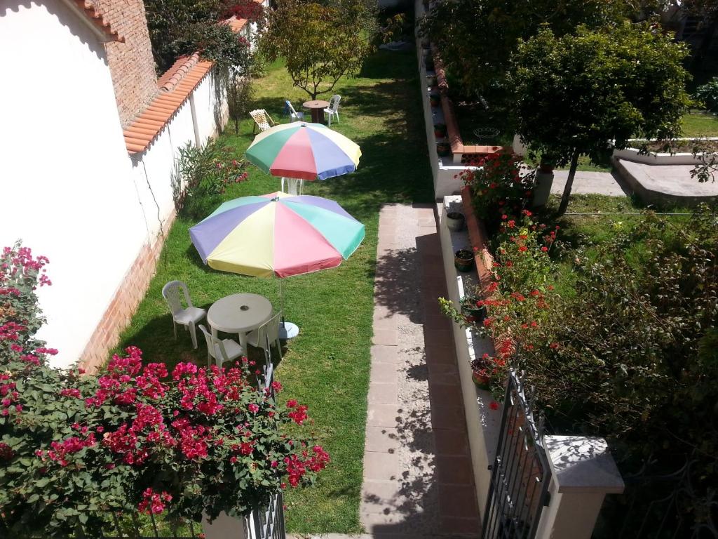 苏克雷Villa Oropeza Hostel的草地上带两把遮阳伞的庭院