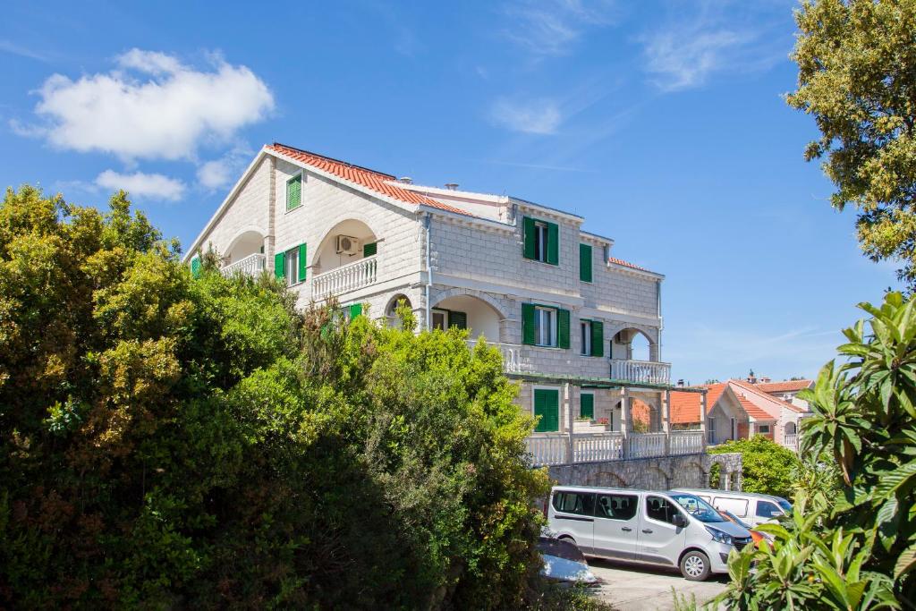 科尔丘拉Apartments Chiara的一座带绿色百叶窗的建筑,前面有停车位