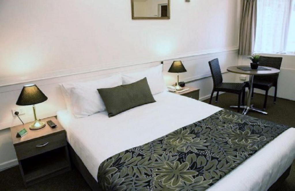 布里斯班花园城汽车旅馆的酒店客房带一张床、一张桌子和椅子