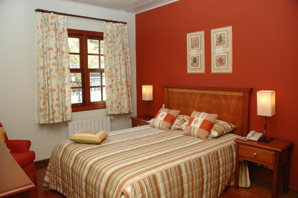 坎波斯杜若尔当夏布利酒店的一间卧室设有一张带红色墙壁的大床