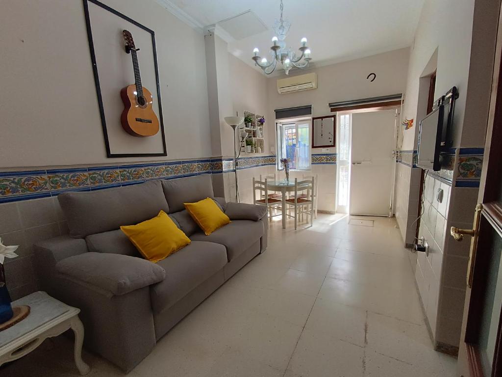 塞维利亚Típico y pintoresco patio de vecinos, con encanto的客厅配有沙发和带吉他桌的桌子