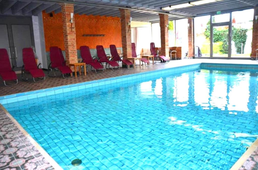 奥格斯堡Ringhotel Alpenhof - Patchworkhotel的一个带红色椅子的大型游泳池