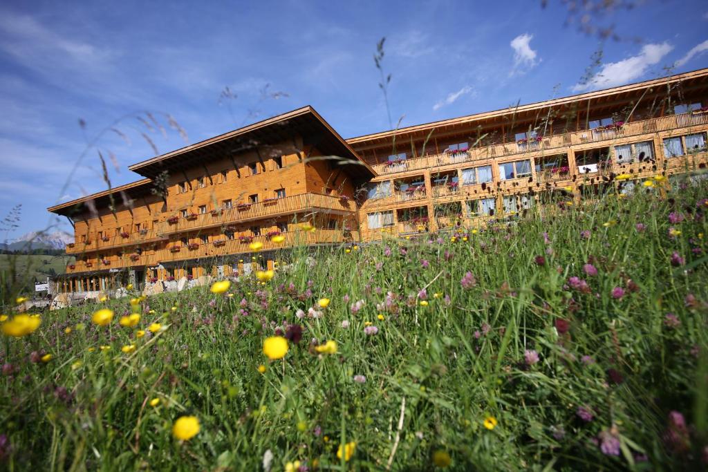 阿尔卑斯休斯山弗罗拉皮那运动酒店的一座建筑前面有花田