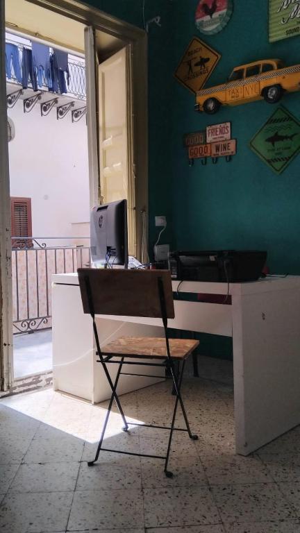巴勒莫Sunshine Hostel Palermo的一张椅子,放在带电脑的桌子上