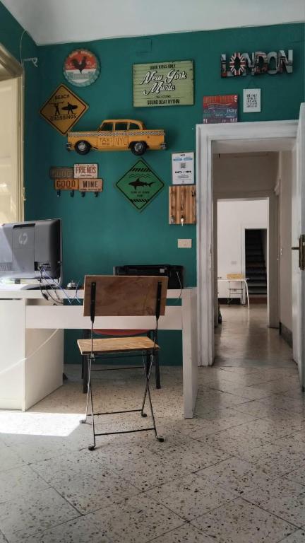 巴勒莫Sunshine Hostel Palermo的房间里有一张桌子，桌子上有一台电脑，墙上挂着标志