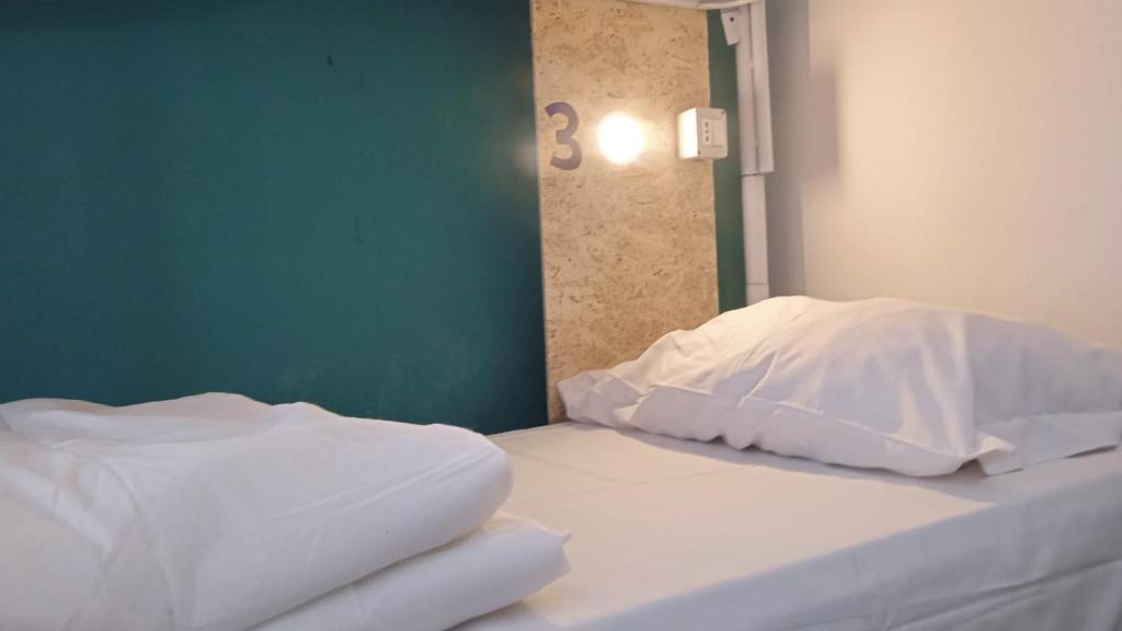 巴勒莫Sunshine Hostel Palermo的房间里有一张铺着白色床单和枕头的床