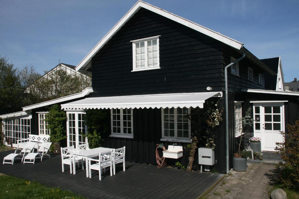胡姆勒拜克Villa Humlebæk B&B的黑色房屋,设有1个带桌椅的甲板