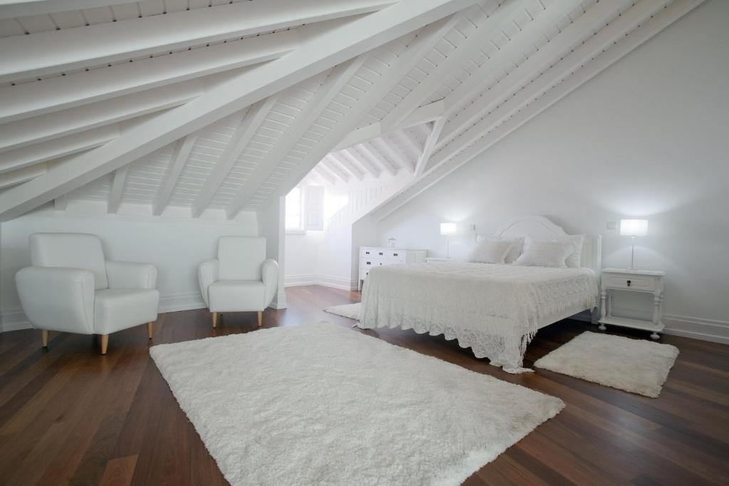 蓬德利马Mercearia da Vila的白色卧室配有白色的床和两把椅子