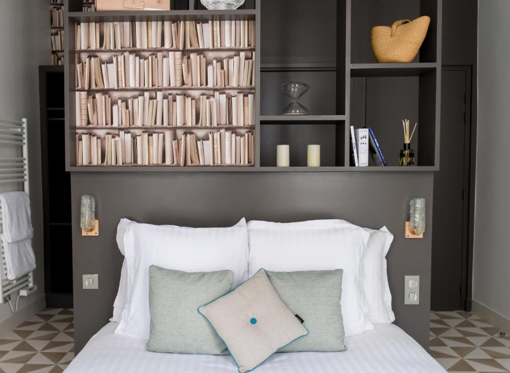 巴黎艾塔吉歌剧1号酒店的一张带白色枕头的床和一个带书籍的书架
