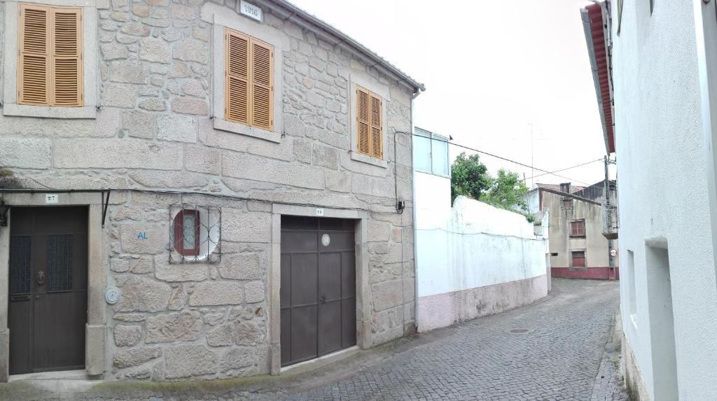 Póvoa de Rio de MoinhosCasa da Rosa的街道上一座石头建筑,设有两扇车库门