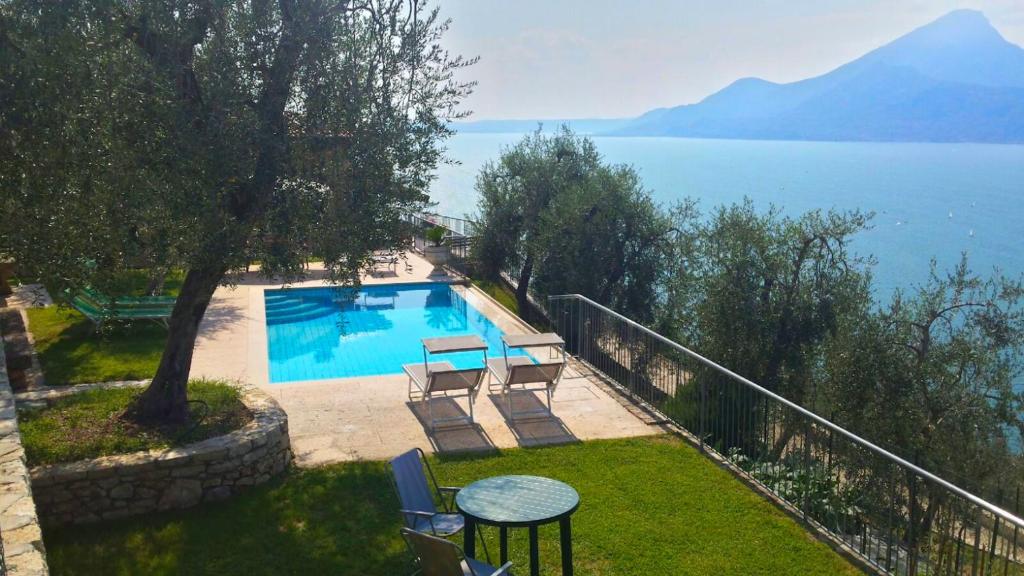 布雷佐内加尔达Agricampeggio Relax (Campsite)的水边的游泳池配有桌椅