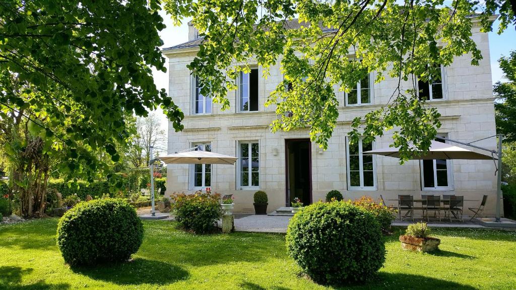 GauriacL'ESCALE DE BEL AIR Chambres d'hôtes的院子里有两把遮阳伞的大型白色房子