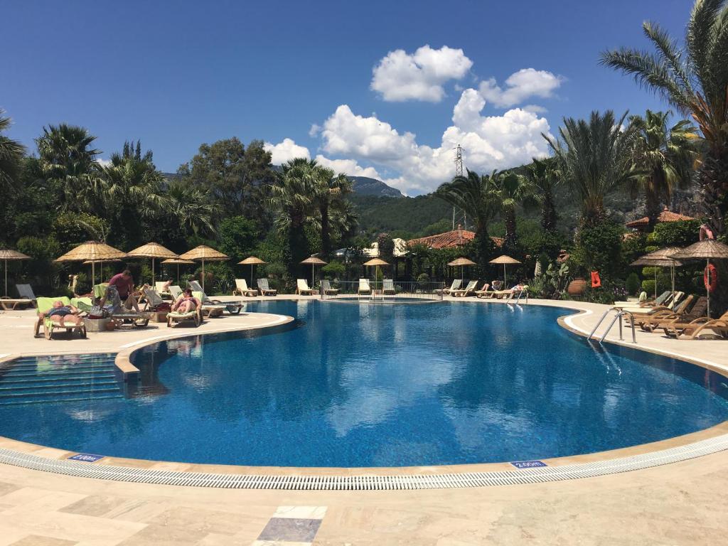 达利安Asur Hotel & Aparts & Villas的度假村内带椅子和遮阳伞的大型游泳池