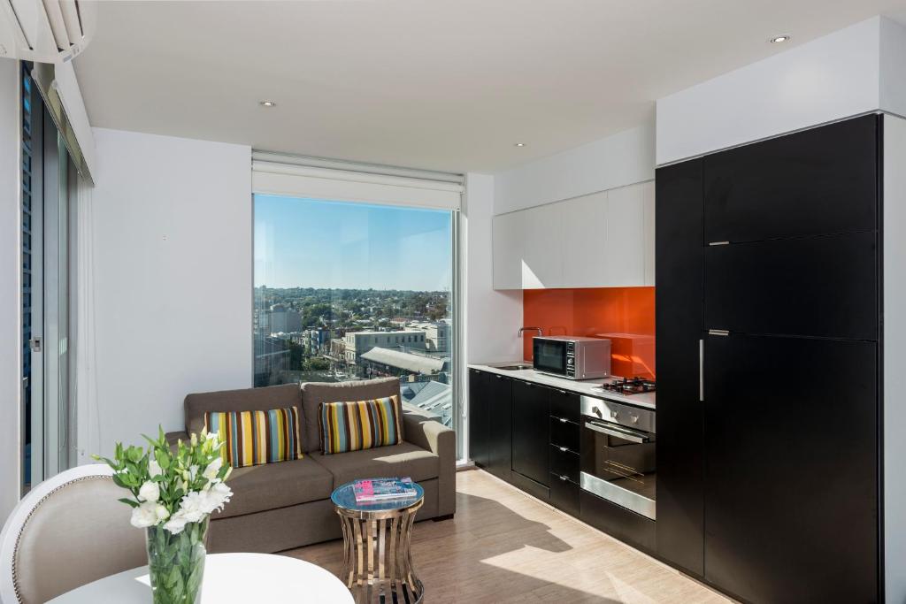 墨尔本Oaks Melbourne South Yarra Suites的厨房以及带沙发和桌子的客厅。