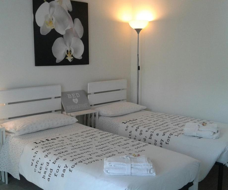 罗扎诺艾玛住宿加早餐旅馆的配有2张床的带白色床单和灯的客房