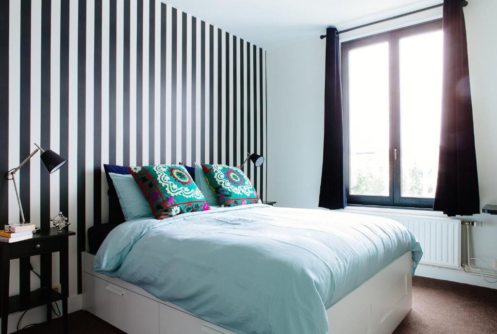 布鲁塞尔朱丹宫殿住宿加早餐旅馆的一间卧室配有一张带黑白条纹墙的床