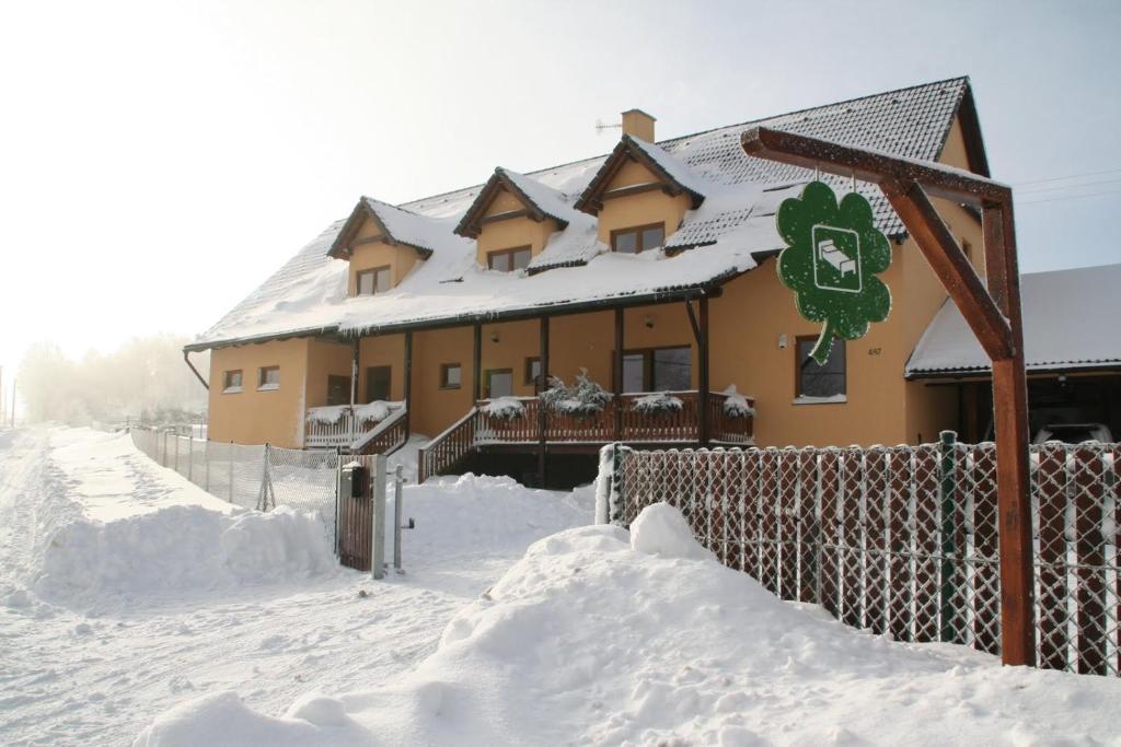 蒂萨萨里斯德克膳食公寓的一座雪覆盖的房子,前面有栅栏