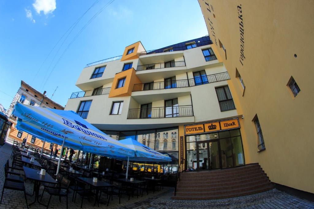 利沃夫塞萨尔酒店的前面有桌子和伞的建筑