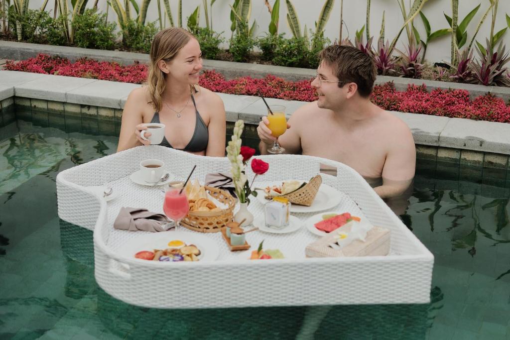 乌布Luxury Nanda villa Ubud的坐在游泳池里吃着饭的男人和女人