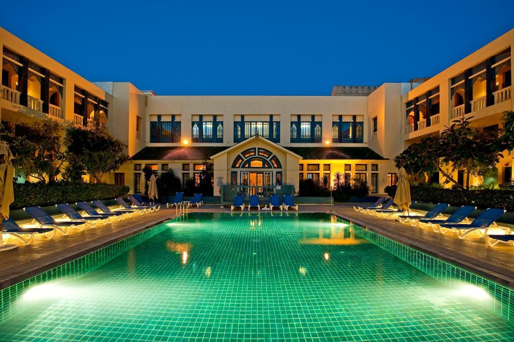 哈马马特迪亚尔雷迪纳酒店的一座游泳池,在晚上在建筑物前