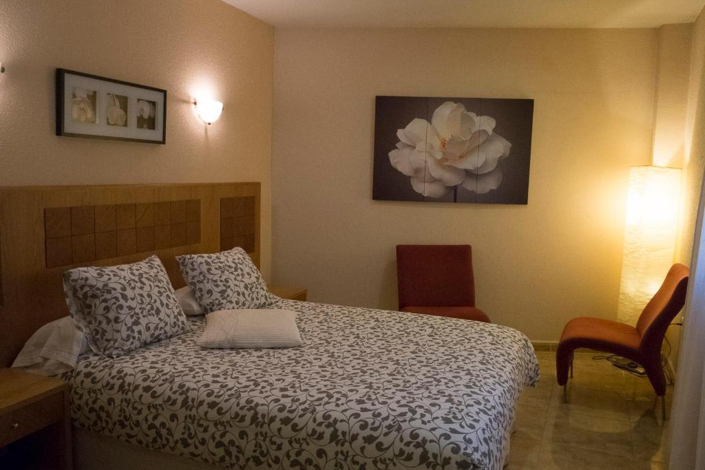 埃尔莫拉尔阿祖尔旅馆的卧室配有一张挂有花卉画的床铺。