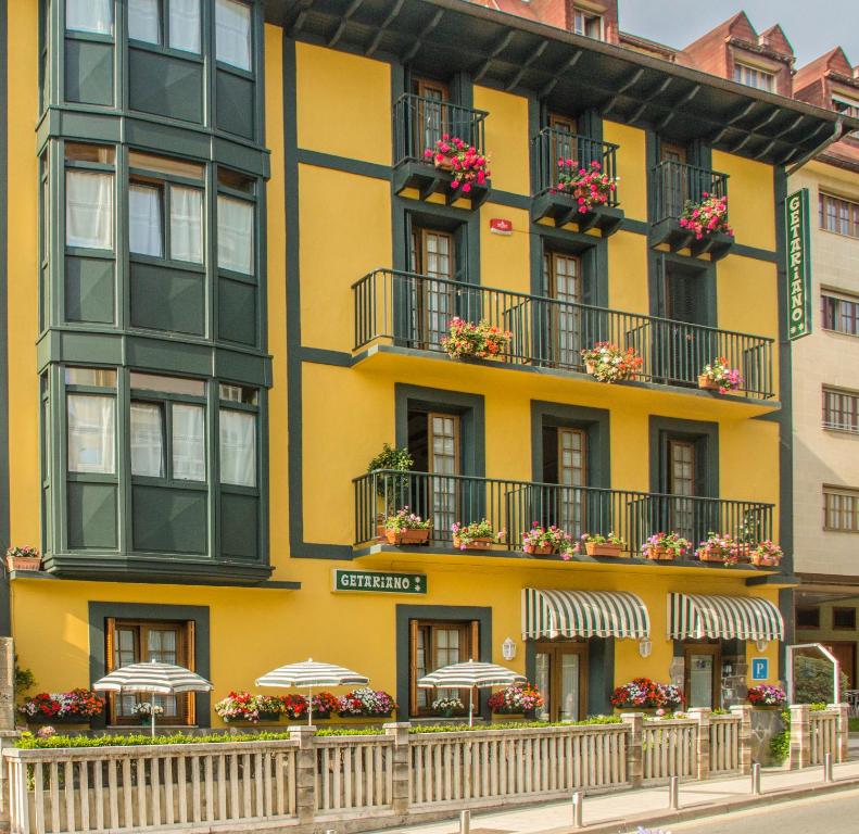 吉塔里亚赫塔里亚诺膳食公寓的带阳台和遮阳伞的黄色建筑