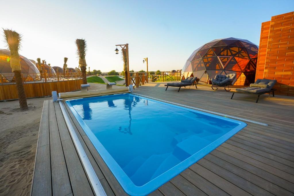 迪拜Al Marmoom Oasis Luxury Experiential Desert Domes的甲板上的游泳池,有两个圆顶
