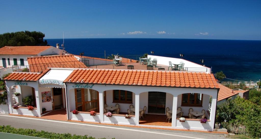 ChiessiHotel Aurora的一座白色的房子,有橙色的屋顶和大海