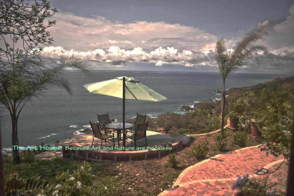 蒙特苏马Montezuma Heights的一张桌子和椅子,配有雨伞和大海