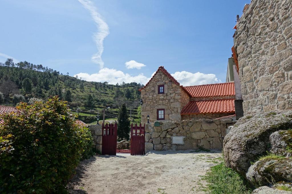 塞亚Casas da Fonte - Serra da Estrela的一座石头房子,有红色的屋顶和石墙