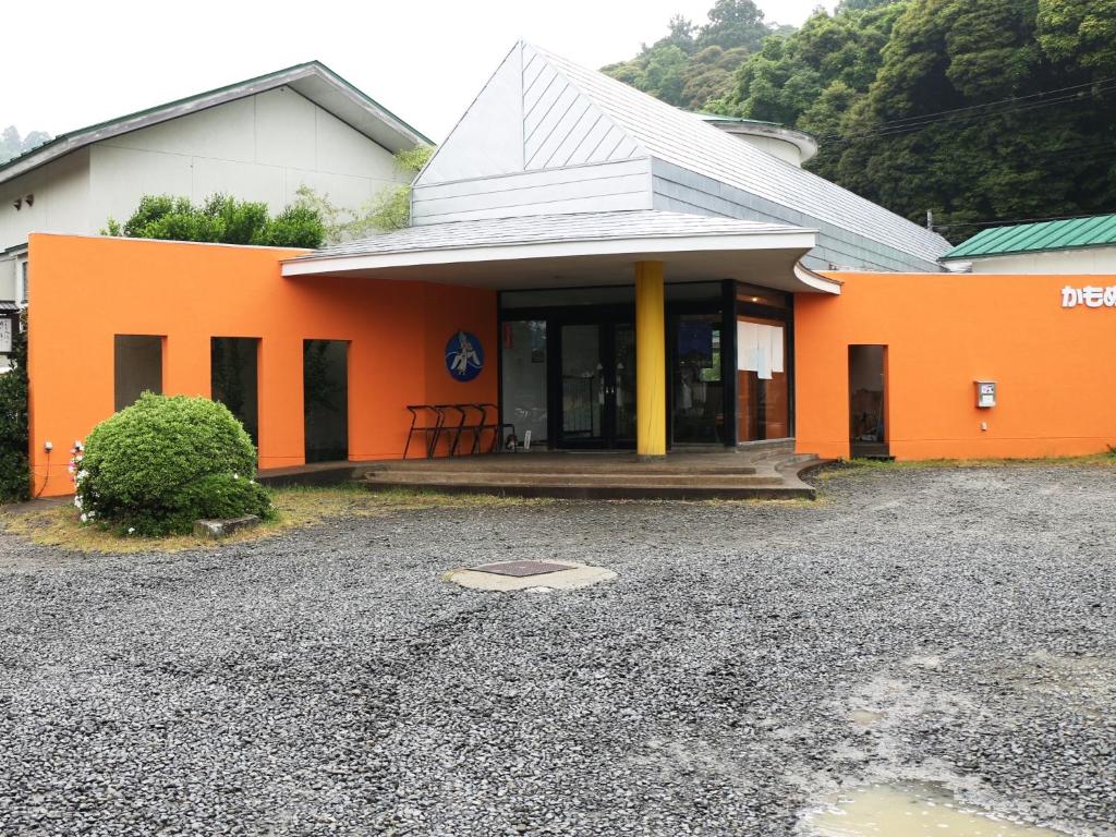 佐渡市海鸥庄旅馆的一座橙色和白色的建筑,设有门廊