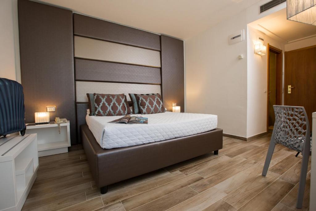 波吉邦西托斯卡纳大使酒店的一间卧室配有一张大床和一把椅子
