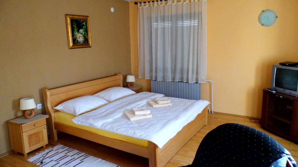 武科瓦尔Apartmani Maraton的一间卧室配有一张带白色床单的床和一台电视。