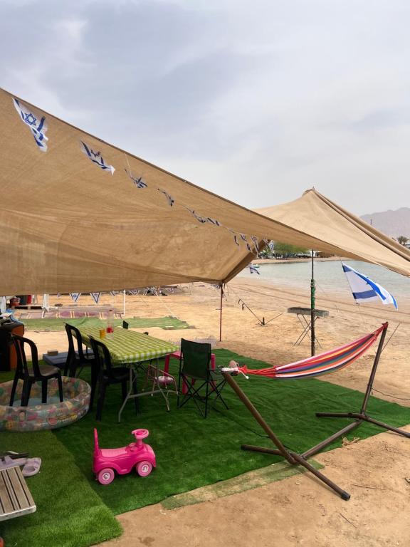 埃拉特קרוואן על הים的沙滩上的帐篷，有一张桌子和一辆玩具车