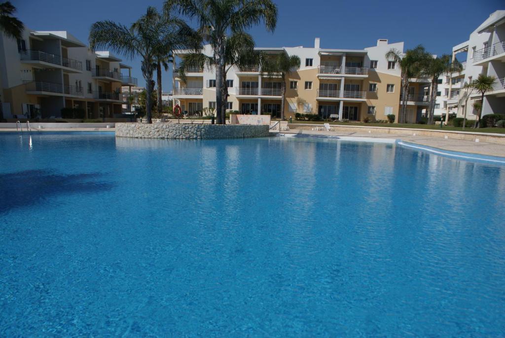 阿尔沃尔Vila da Praia 7D Alvor的一个大型蓝色游泳池,其建筑背景为: