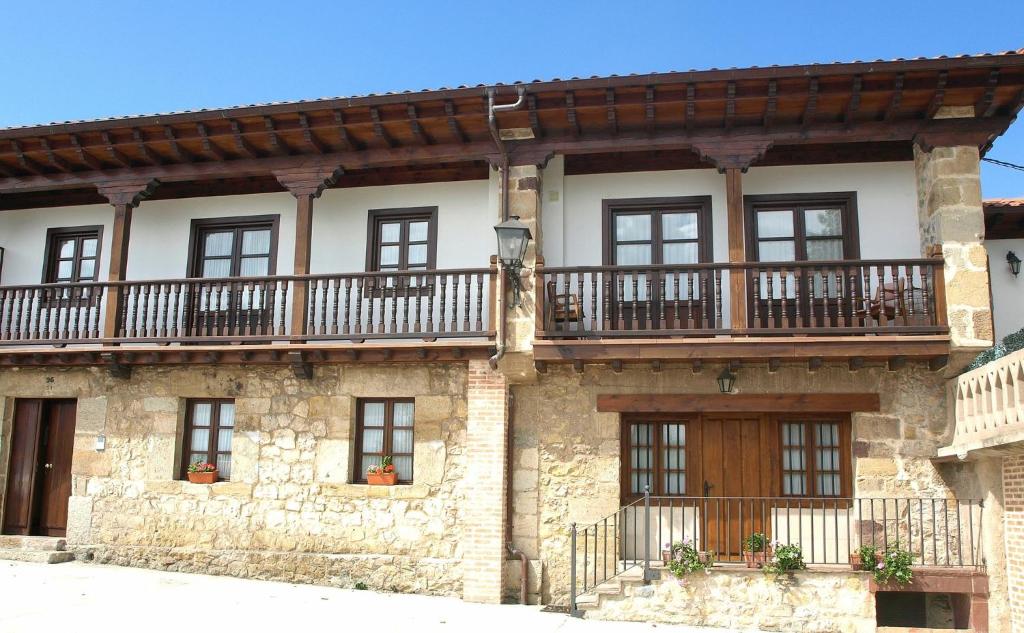 桑提亚纳德玛Apartamentos LLave de Santillana的一座古老的石头房子,上面设有阳台